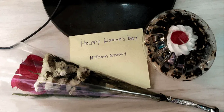 Women's Day note, flower and cake left on a desk by Team Groovy
