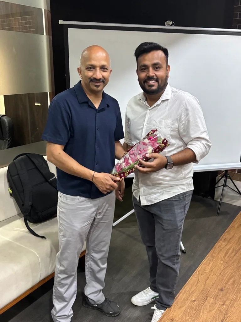 Two men posing with a bouquet during a client visit at the Groovy Web office